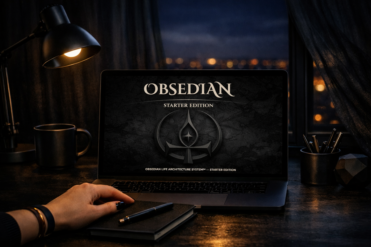 Nighttime workspace with laptop displaying OBSEDIAN Life Architecture System Starter Edition, black desk, warm lamp light, and city lights through sheer curtains.